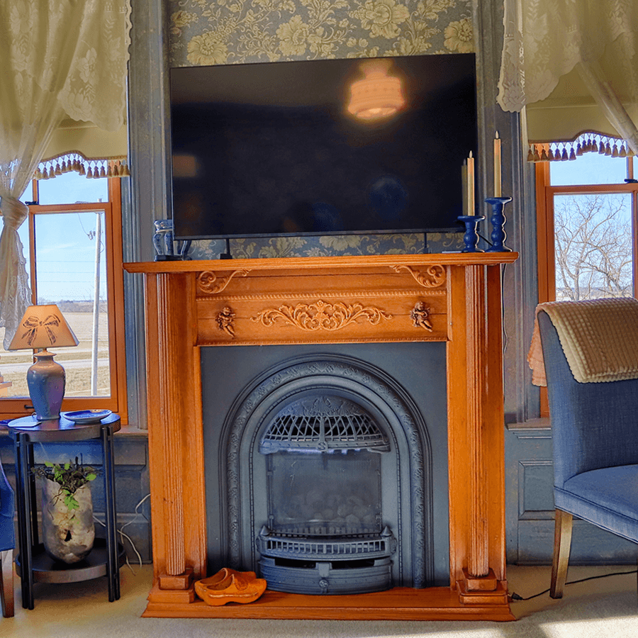 A wooden fireplace with intricate carvings, a modern TV above it, and decorative elements in a cozy room.