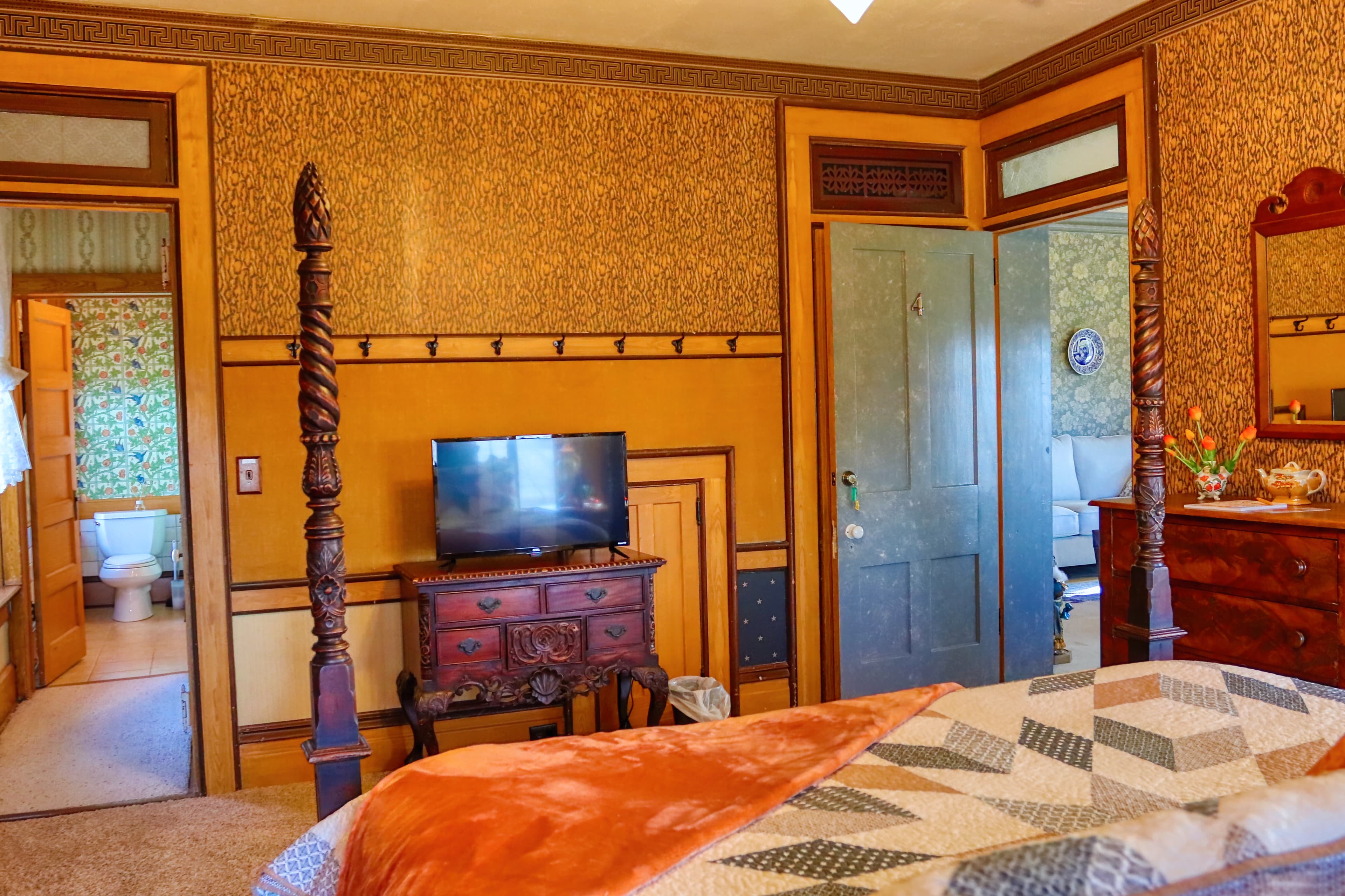 A cozy bedroom with a quilt-covered bed, wooden accents, and a floral rug.