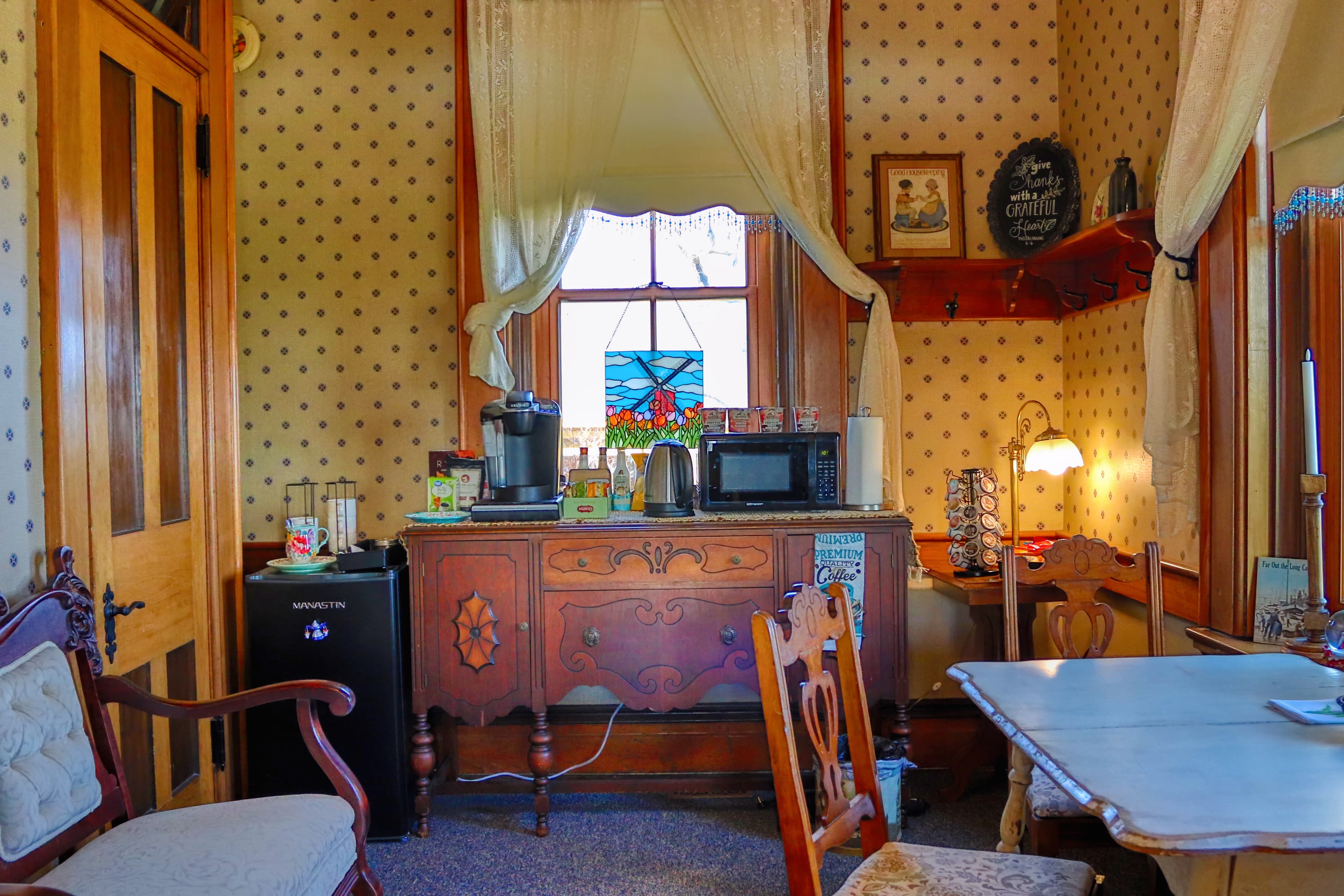 A cozy kitchen corner with vintage decor, a wooden cabinet, and a window featuring stained glass.