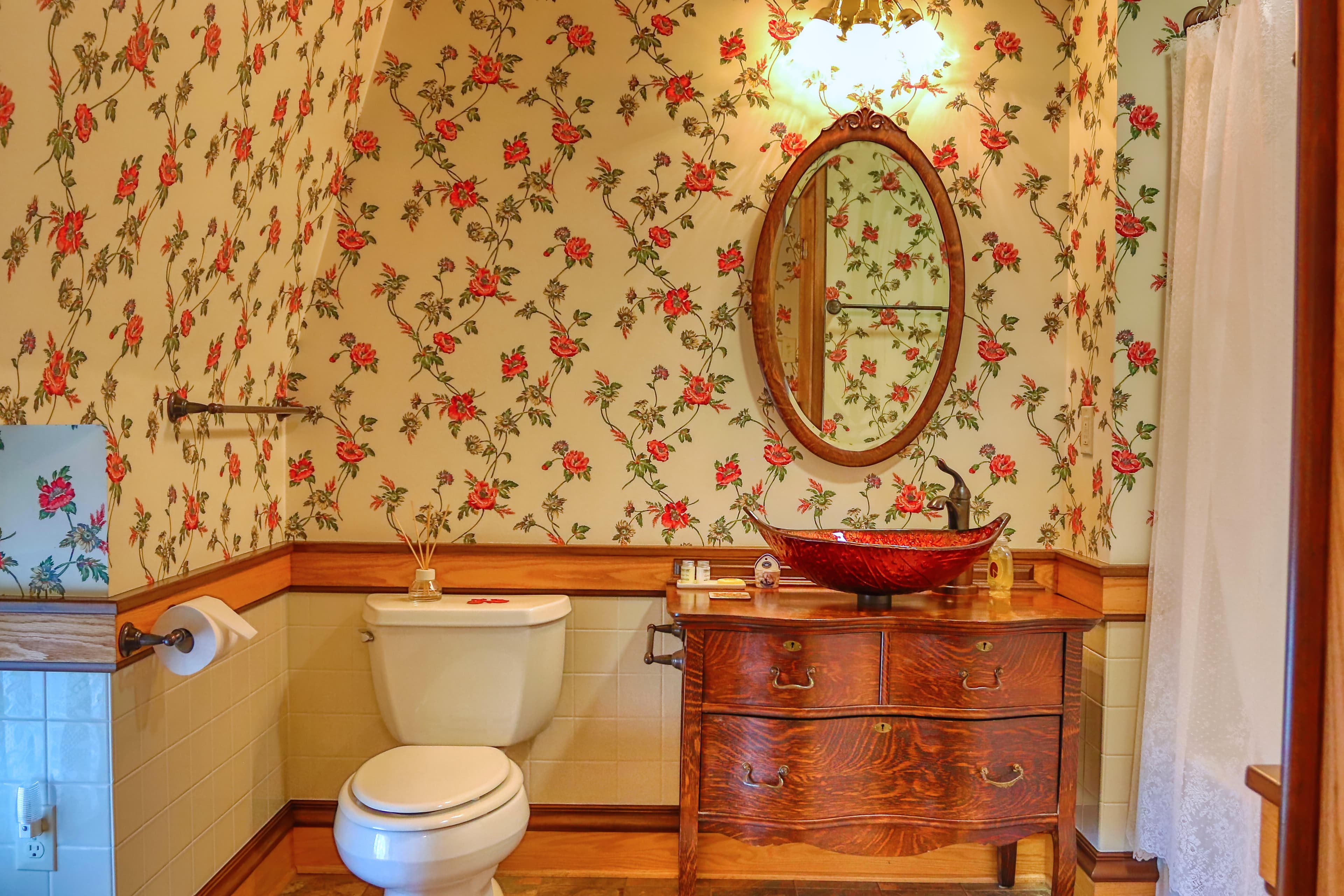 Vintage-style room with striped floor, pink sofa, red rug, and floral wallpaper.