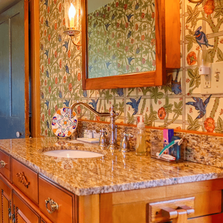 A stylish bathroom sink area featuring a floral patterned wall, granite countertop, and wooden accents.