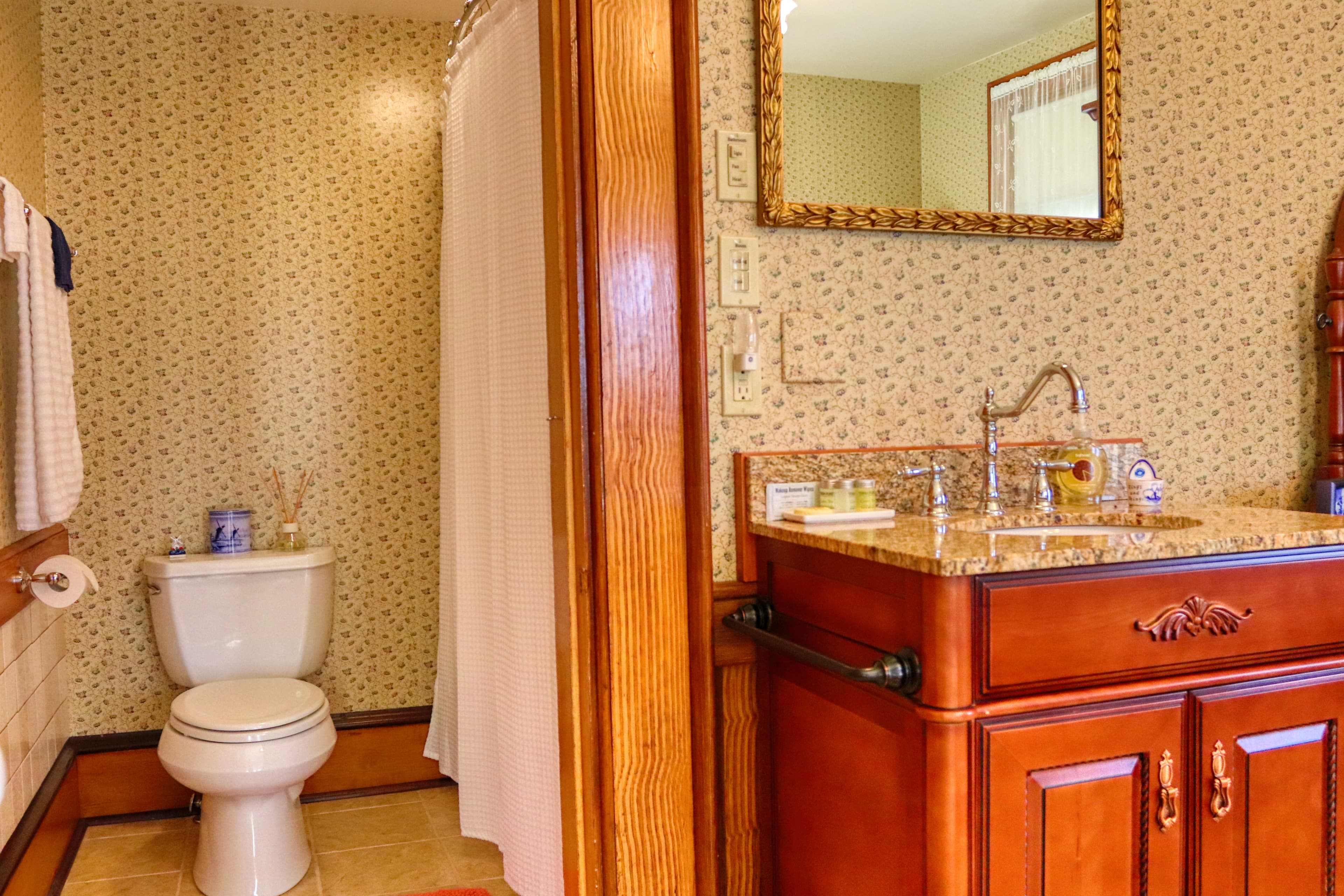A bathroom interior with toilet, vanity sink, and framed mirror.