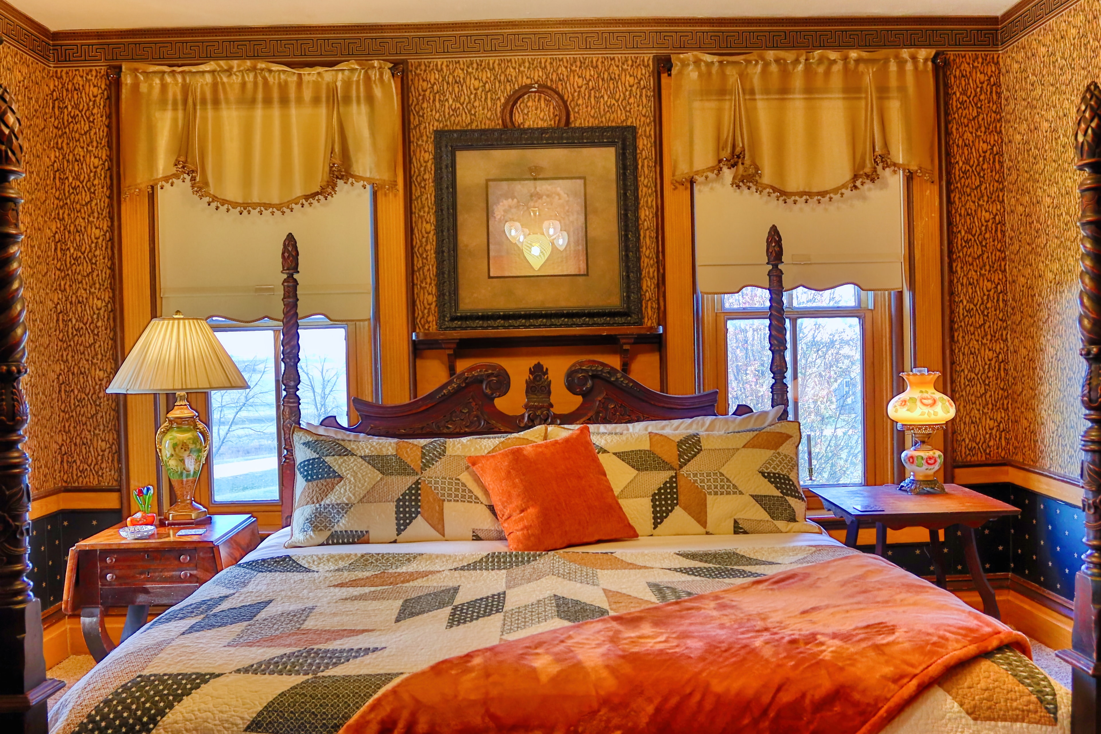 Elegant bedroom with four-poster bed, wooden furniture, and patterned wallpaper.
