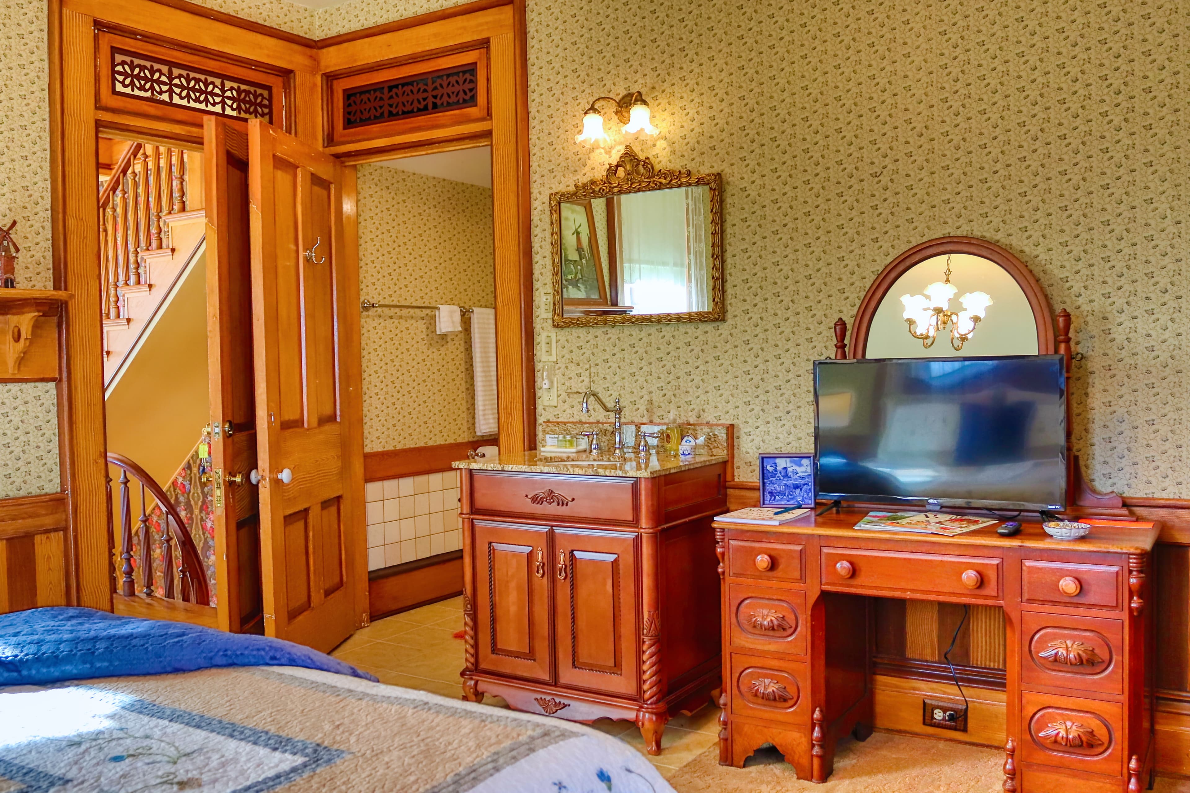Vintage furnished bedroom with quilted bed, wooden wardrobe, and dressing table.