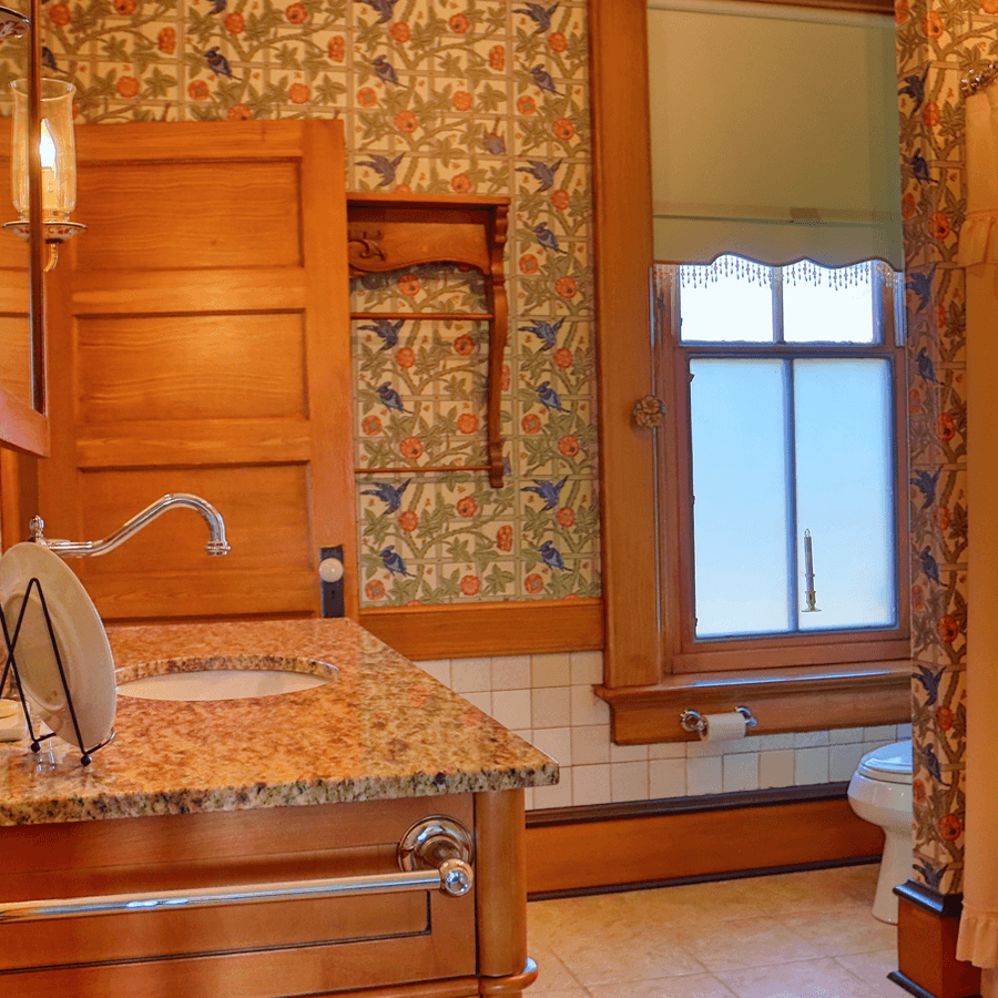 Vintage bathroom featuring floral wallpaper, wooden accents, and a granite countertop with a sink.